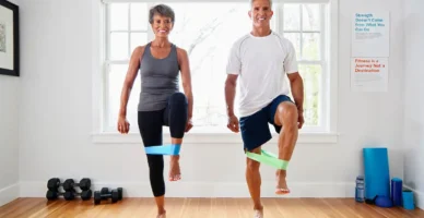 “Pareja de más de 50 años haciendo ejercicios suaves con bandas elásticas para fortalecer las articulaciones y mejorar la movilidad.”