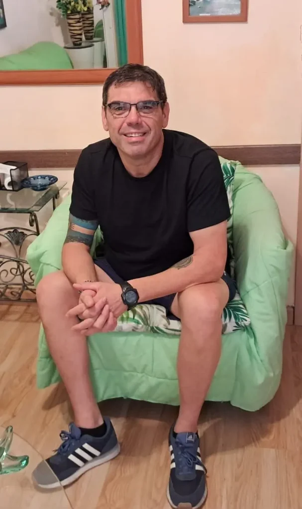 “Leo, fundador de FitZone50, sentado en su sofá antes de comenzar su transformación con entrenamiento funcional a los 53 años.”